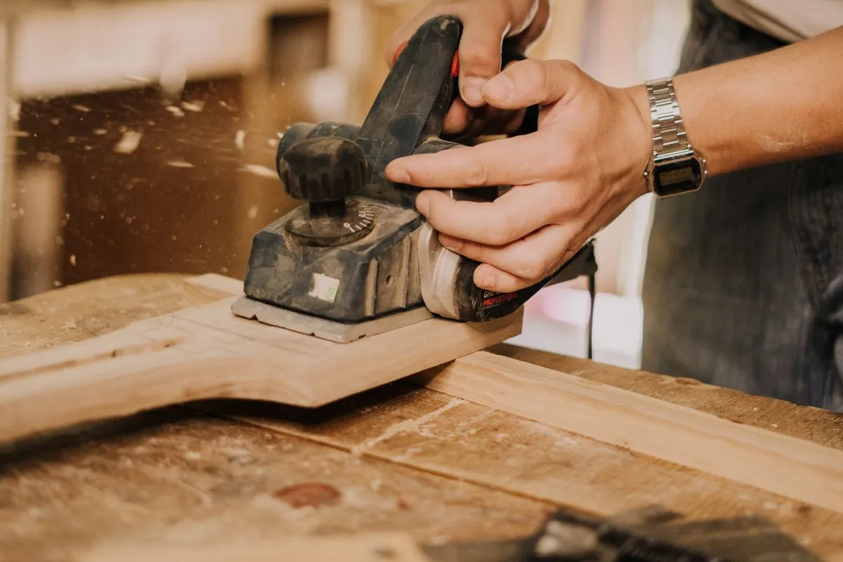 Carpenter planing a piece of trim by hand