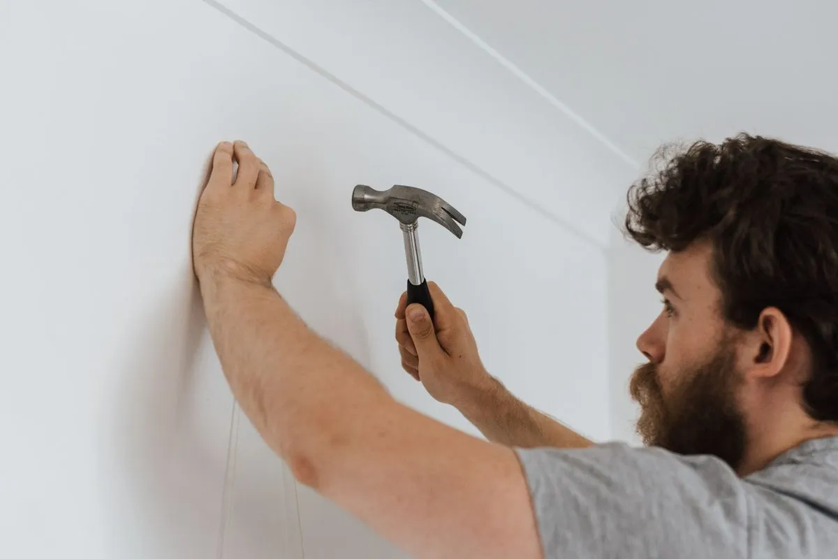 Handyman hanging a picture on a freshly painted wall