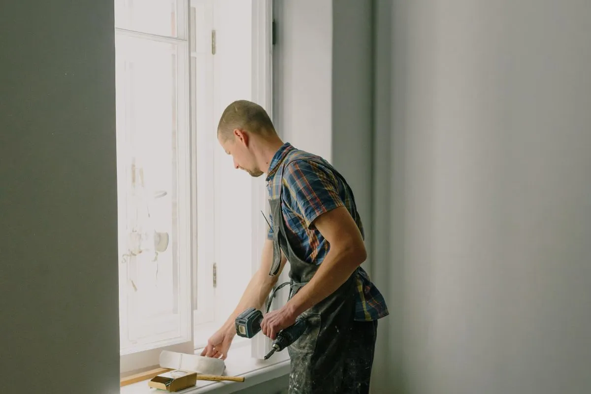 Handyman with a drill working at a window sill